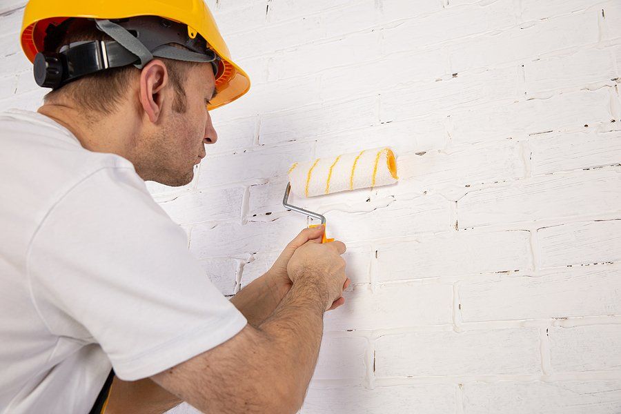 man in yellow hat applying paint in the walls